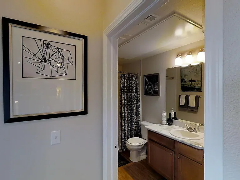 Apartment bathroom with wood-style flooring.