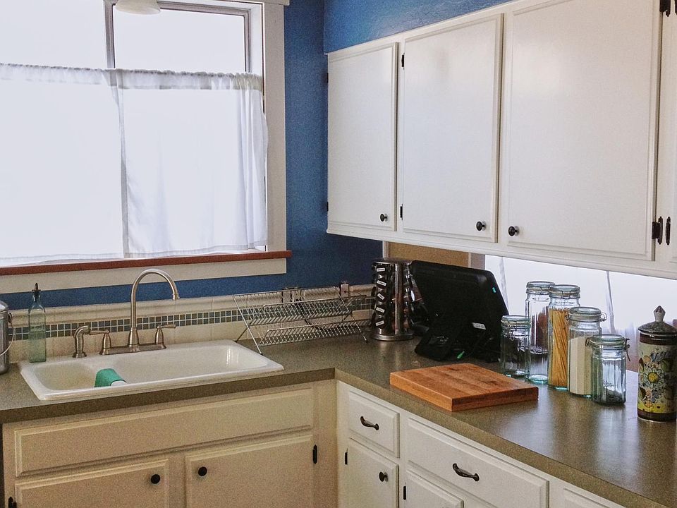 Kitchen with dual sink, tile backsplash, and hardwood floor.