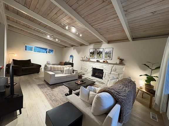 Living Room (Wide View): Spacious living room with vaulted, wood-beam ceiling and abundant natural light.