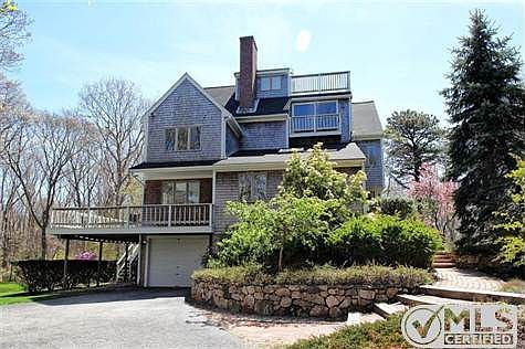 Exterior view of house showing stately stone wall and walkway to front door.