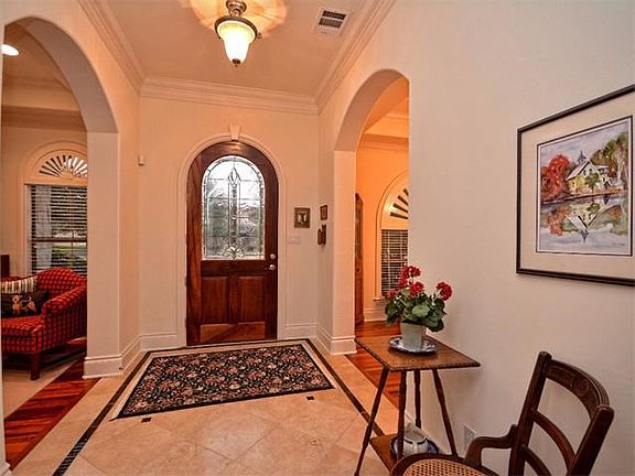 The inviting foyer features a beautiful hardwood door, two-step crown and terrazzo tile flooring.