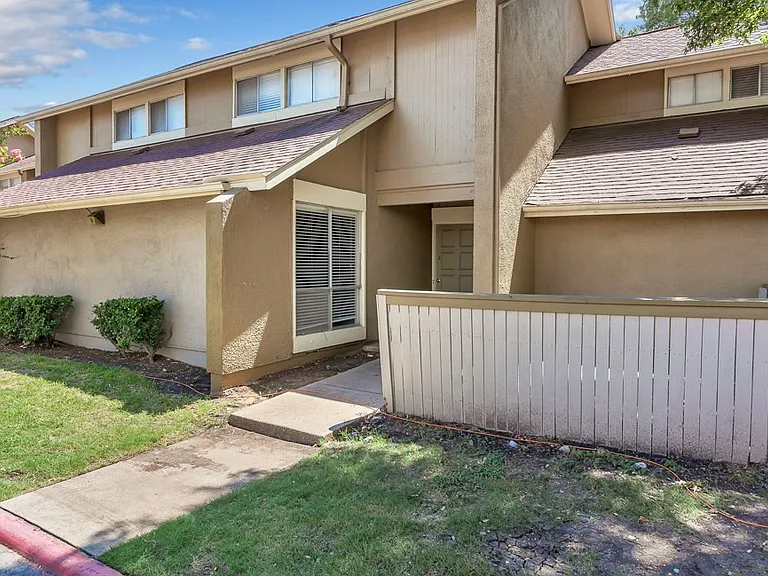 Townhome-style apartment exterior with private fenced patio and landscaped walkway at Watersong Villas Apartments in North Dallas.