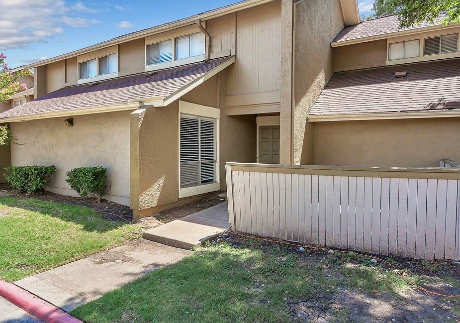 Townhome-style apartment exterior with private fenced patio and landscaped walkway at Watersong Villas Apartments in North Dallas.