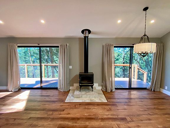 The cottage great room includes a wood stove and dining area with pendant light. The light can be removed or height adjusted to meet tenant needs.