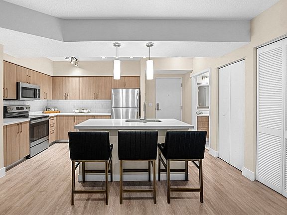 Modern kitchens include USB charging ports, islands, pendant lighting, wood-grain cabinets and stainless steel appliances