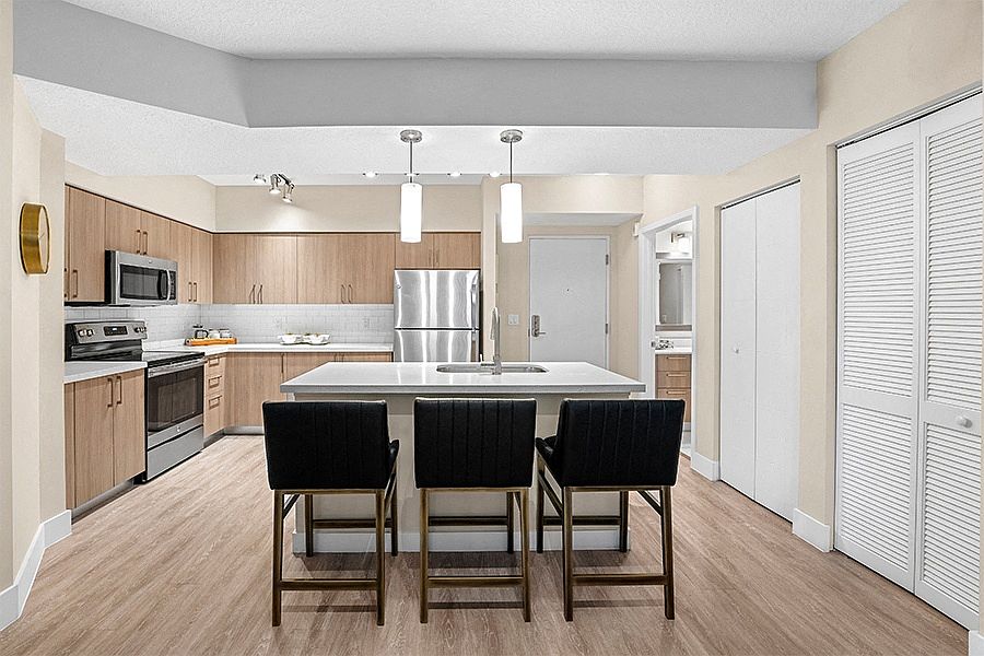 Modern kitchens include USB charging ports, islands, pendant lighting, wood-grain cabinets and stainless steel appliances