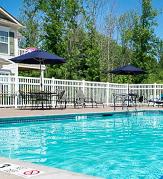 Outdoor swimming pool with large pool deck, tables, and chaise longues