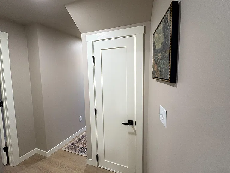 Clean interior hallway with durable flooring, neutral paint, and crisp trim connecting to nearby rooms.