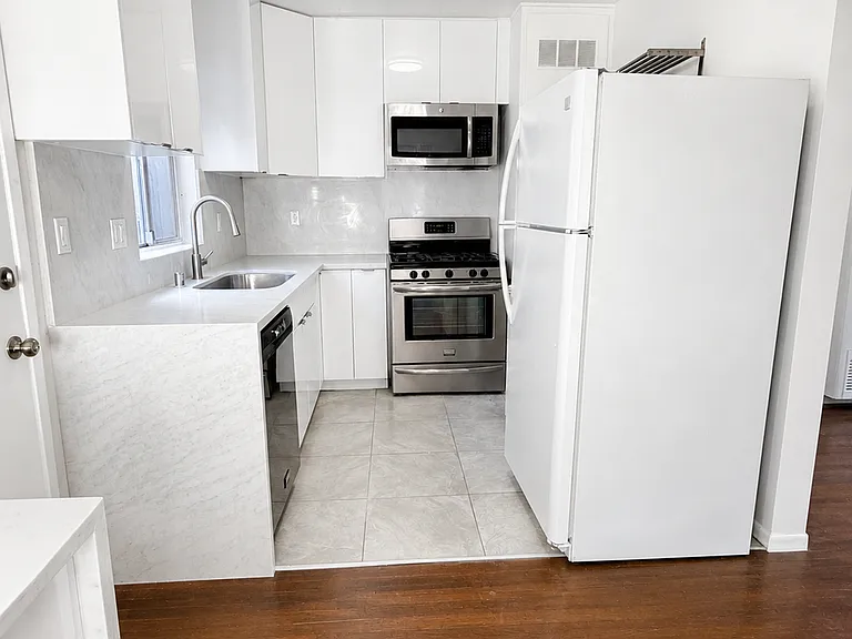 Renovated kitchen with white cabinetry, stone-look counters, stainless steel appliances, and clean modern finishes.