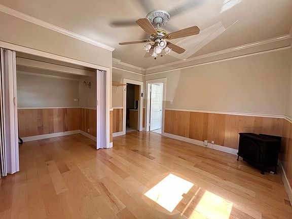 Living room features gas burning stove, ample lighting, Victorian fan and light scones, as well as an office or sleeping alcove with accordion doors for privacy.