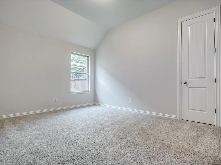 Carpeted room with vaulted ceiling and a single window