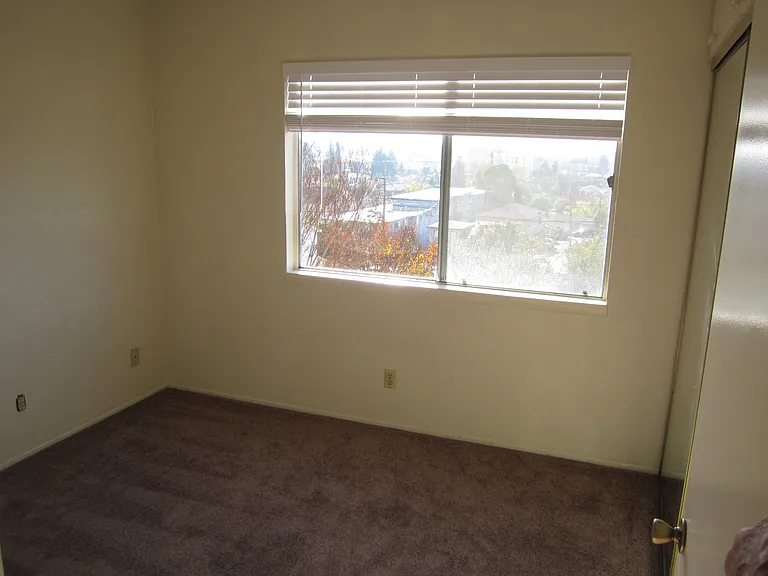 First bedroom on left with large window, mirrored sliding doors with upper cabinets