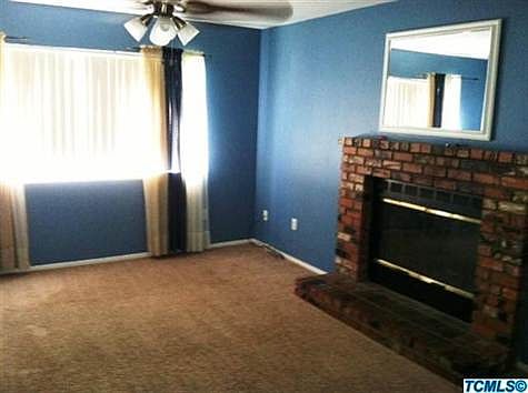 Living room opens to the dining room and kitchen and features fireplace, ceiling fan and new carpet.