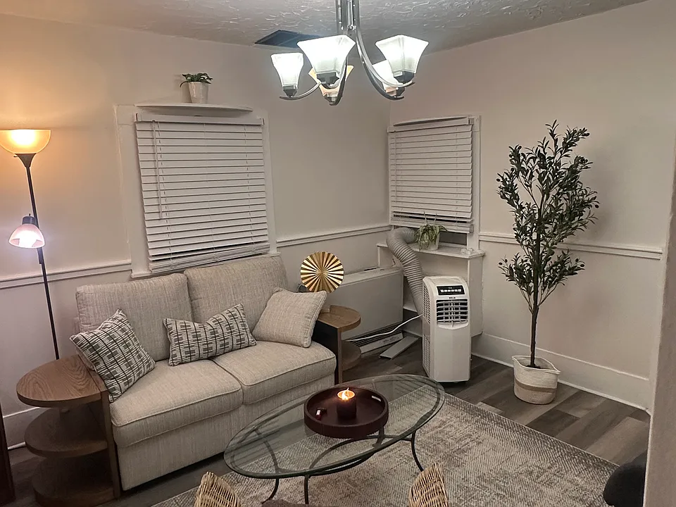 Shared living room furnished with a sofa, coffee table, side tables, television, area rug, and additional furnishings and decor