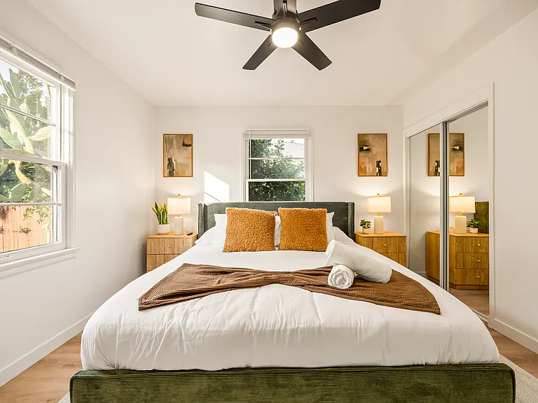 Spacious primary bedroom featuring a king bed, dedicated workspace, ceiling fan, and a calm, relaxing atmosphere ideal for extended stays or working remotely.