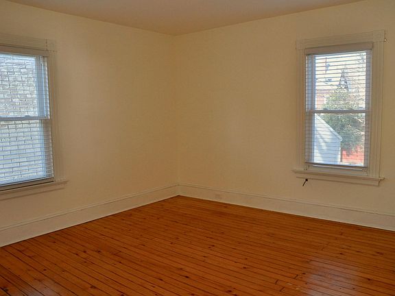 Spacious, sunny living room with wood floors and new wood blinds.