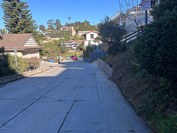 View looking NW down Rideout Way toward the house. The large window in the center of the photo is the owner's living room. Red car is another tenant's. You'll park your skinny vehicle behind it.