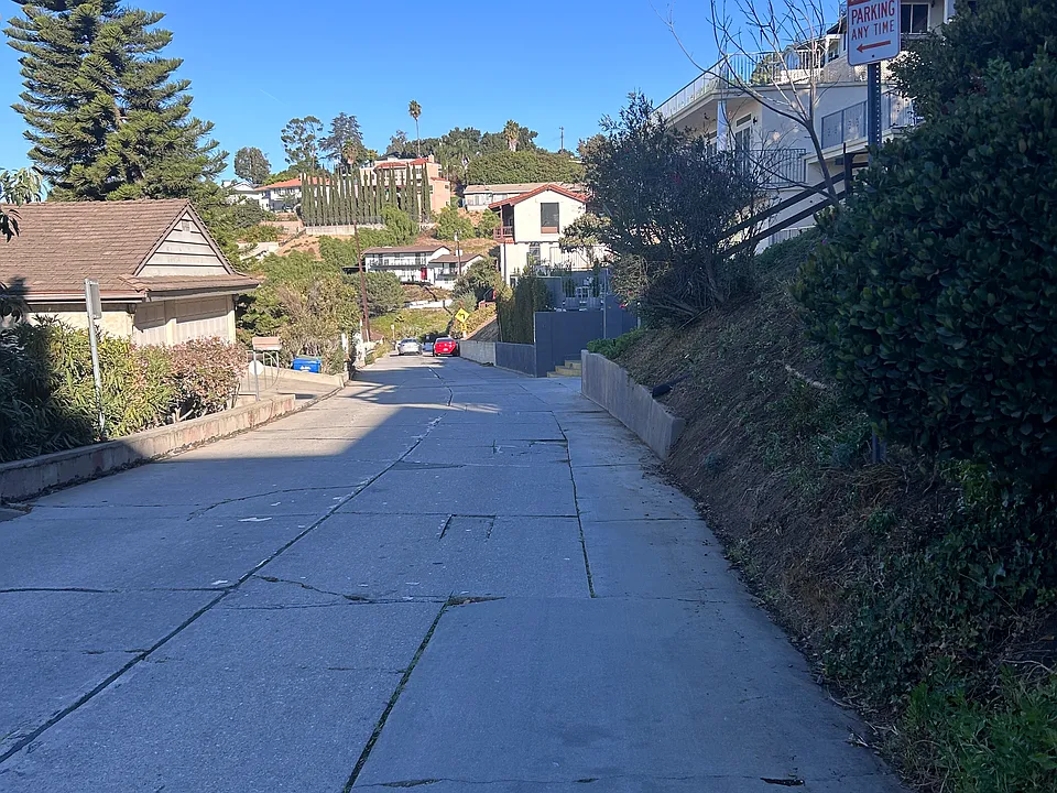 View looking NW down Rideout Way toward the house. The large window in the center of the photo is the owner's living room. Red car is another tenant's. You'll park your skinny vehicle behind it.