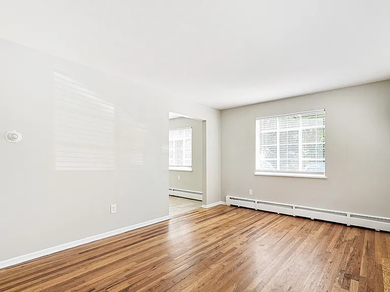 Bright and airy room with large windows and polished hardwood floors, offering versatile space for living or dining.