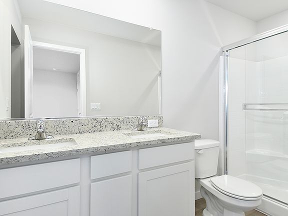 The master bathroom has a dual sink vanity and a step in shower.
