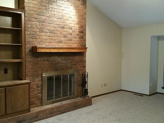 Living room with built in bookcase, new carpet and fireplace.