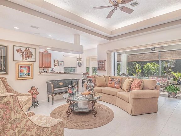 LIVING ROOM OPEN TO KITCHEN AND FULL POCKETING GLASS SLIDING DOORS LEADING TO THE SCREENED LANAI ADDING TO YOUR LIVING SPACE FOR
