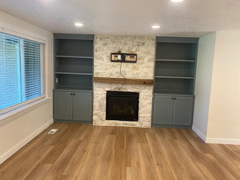 Beautiful living room. Rock fireplace. Laminate flooring. Built in shelves in rich green.