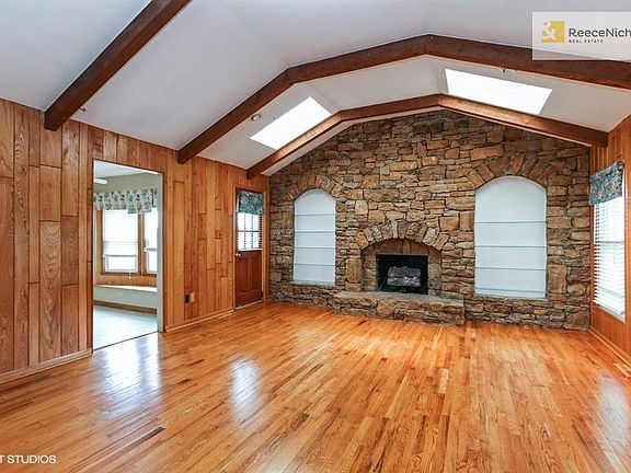Living Room with vaulted ceilings, skylights, built in shelves, and beautiful stone fireplace