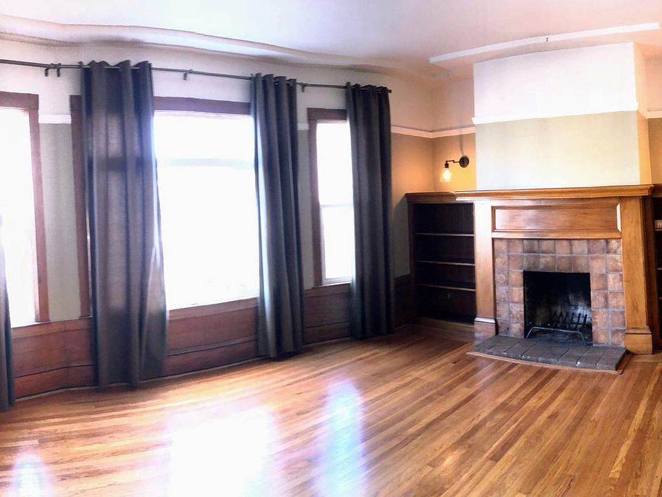 Large living room with wood burning fireplace and book shelv
