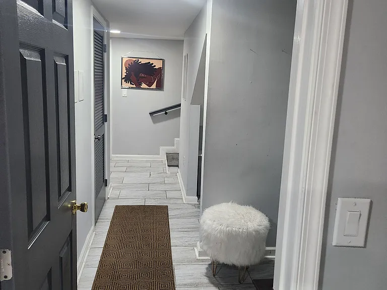 Tiled entry hallway with recessed lighting, neutral finishes, and a stairway with handrail for easy access between levels.