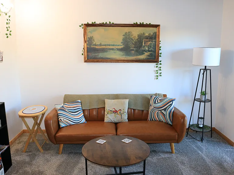 living room with leather couch, coffee table, lamp. patio to the right
