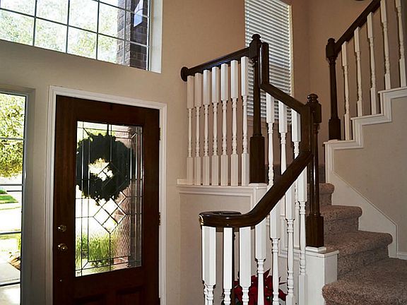 The leaded glass front door opens to a high ceiling, large transom and side window. The floor is tile and leads to the charming staircase.