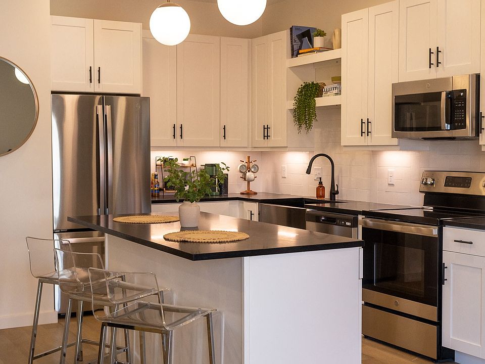 a kitchen with white cabinets and a large island with a black countertop
