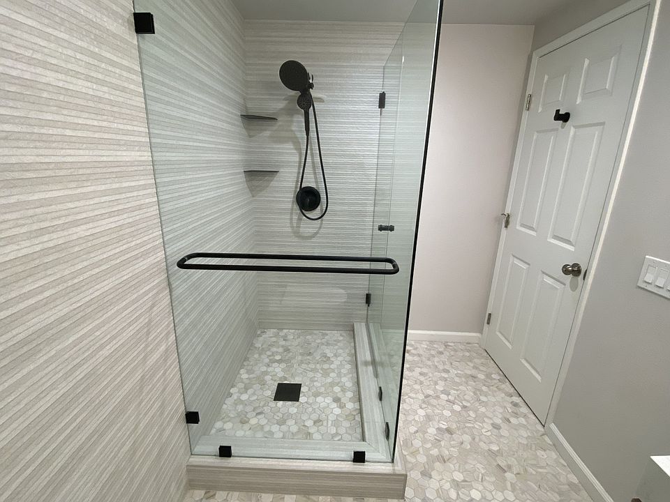 Spacious glass shower with towel fixtures inside and out. It is wider than the picture shows
