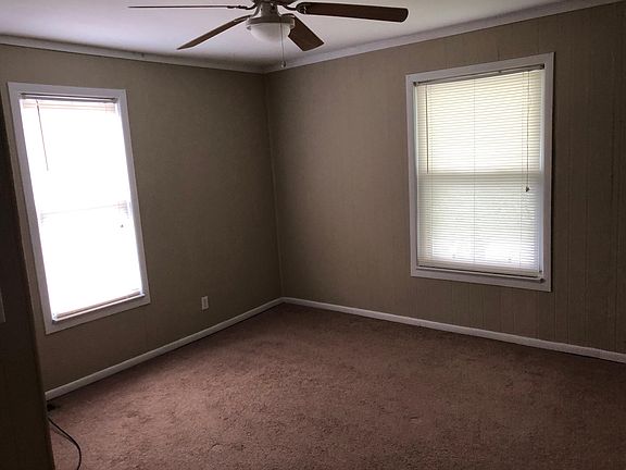 Front bedroom showing large windows, ceiling fan & plush carpet.