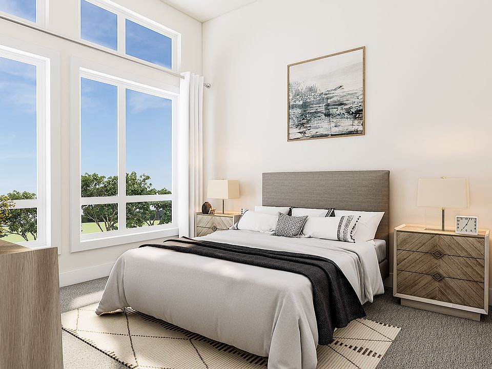 A modern and bright bedroom with large windows overlooking a lush outdoor landscape, featuring a com