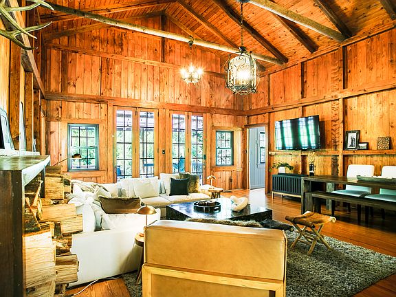 Living room with real wood stove and open loft access. There is one large living space and all four bedrooms are located directly off the living room.