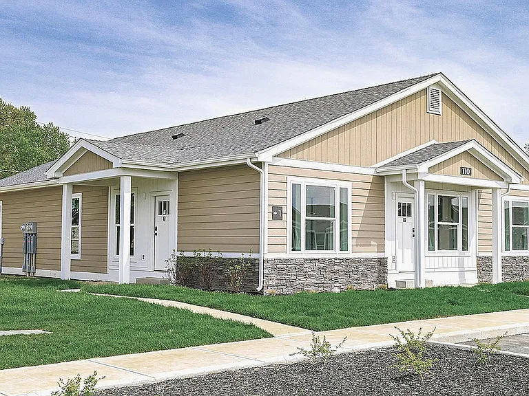 Charming single-story home with beige siding, white trim, and well-maintained green lawn, perfect for modern suburban living.