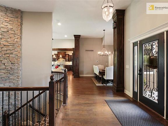 The entryway leads to the formal dining and open living space to the right.  Three bedrooms on opposite wing of the home.  Two-story stacked stone wall and curved stairway to finished lower level.