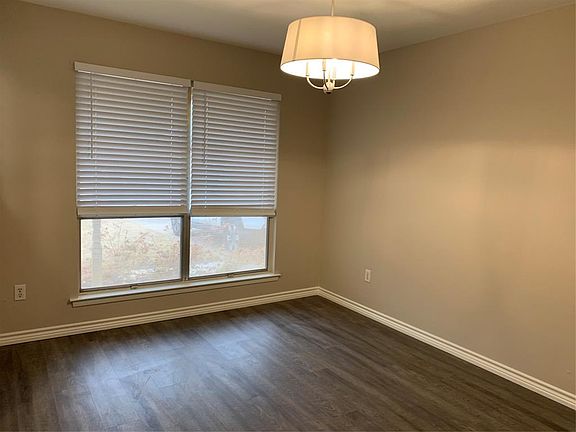 Empty room featuring dark wood finished floors and baseboards