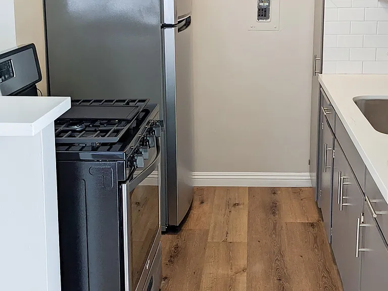 Galley kitchen- stainless appliances, quartz countertop, stainless steel sink, backsplash