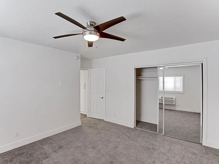 A room with a ceiling fan and a carpeted floor.