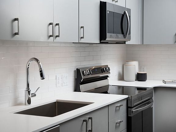Modern kitchens with light grey cabinetry, white quartz countertops, and stainless steel appliances