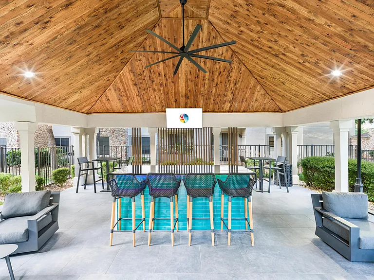 Covered poolside bar with TV, ceiling fan, and plenty of seating_perfect for unwinding or catching the game.
