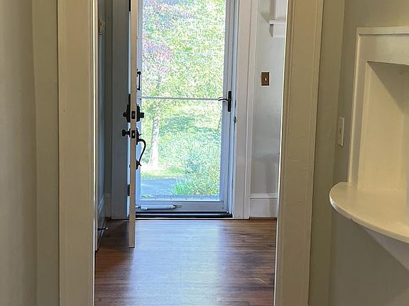 Front door leading to hallway with antique built in phone station