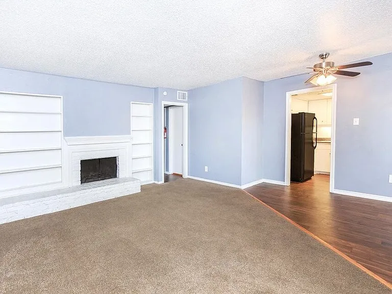 Spacious living room with a cozy fireplace, large window views, and wood-style flooring.