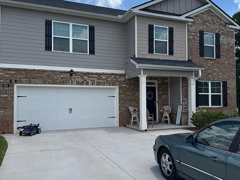 Two-story home with a covered entry, attached two-car garage, and a wide driveway for convenient off-street parking.