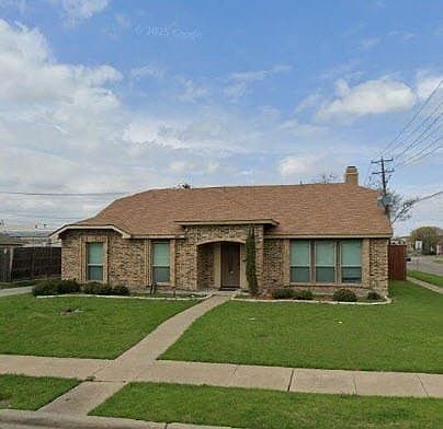 Brick exterior residence with a brown shingle roof