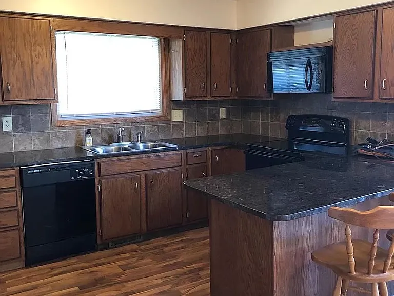 Kitchen features granite countertops, laminate floors, and tile backsplash