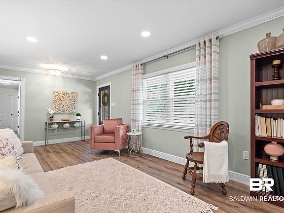 Spacious living area featuring wood-finish flooring, recessed lighting, crown molding, and a large window with white blinds